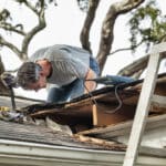 Man Examining and Repairing Rotten Leaking House Roof